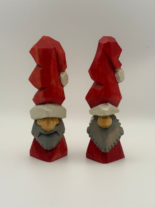 Two wooden gnomes with red hats and gray beards on a white background
